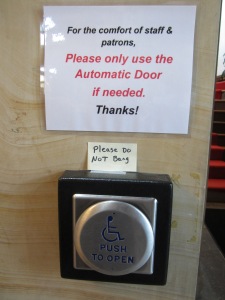 Laminated sign over post-it over button to open door mechanically