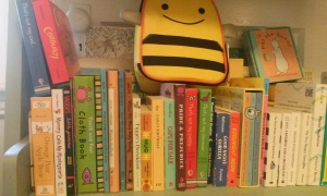 Shelf of board books with bee lunchbox on top