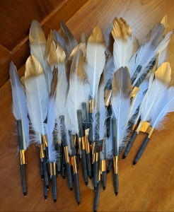 Gold-tipped feathers attached to pens