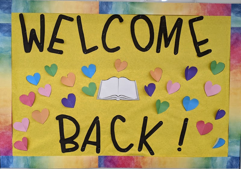 Bulletin board with WELCOME BACK message and paper hearts and rainbow border